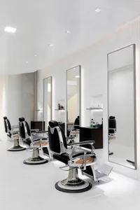 Modern barber shop with metal chairs and mirrors.