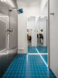 Modern bathroom featuring glass walls and blue tiled floor and walls.