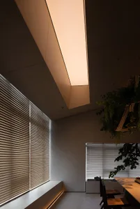 A modern dining room with metallic blinds and green plants