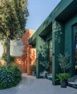 A modern exterior featuring brick and concrete rendered walls and green plant pots.