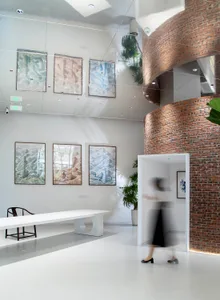A modern, industrial-style lobby featuring white walls, red brick columns, and white furniture.