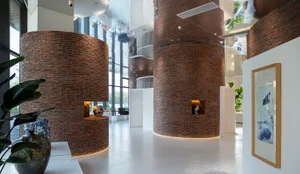A modern lobby with large brick columns and concrete flooring.