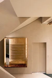 A modern metal-clad staircase with glass railings in an entryway with ambient lighting.
