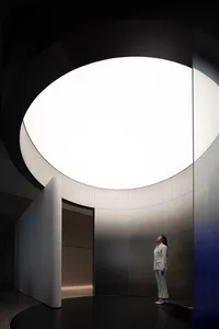 A minimalist interior space with metallic surfaces and circular lighting