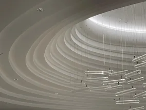 A modern office space features glass lighting fixtures hanging from the ceiling.