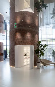 High-ceilinged, minimalist office space featuring exposed concrete columns and floor-to-ceiling windows.