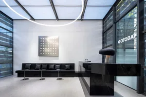 A spacious modern office space featuring a metal and glass design with a black reception desk and minimalist decor.
