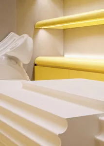 Modern bedroom with yellow plastic headboard and bedding.