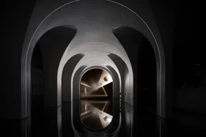 A modernist architectural space featuring metallic arches and reflective surfaces.