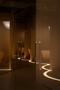 A modern corridor with illuminated concrete flooring and walls, featuring a winding light path.