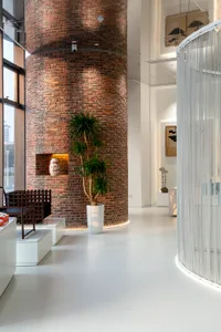 A modern industrial office featuring a large brick column and minimalist design elements.