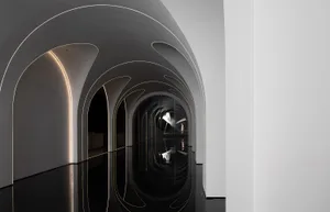 A minimalist, black and white architectural interior with curved glass walls and a reflective floor.