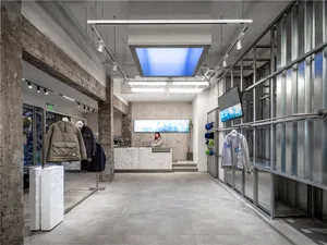 現代零售店內部，混凝土牆面與地板，搭配服裝展示架與接待櫃台。