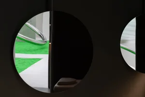 Circular window revealing green flooring and white, curved architectural elements.