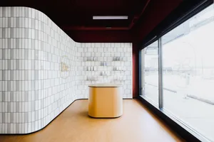 A modern retail space featuring white tiled walls and a yellow counter.