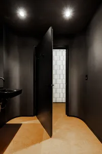 An open, black metal door in a minimalist bathroom setting.