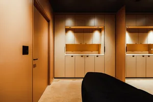 Modern, minimalist storage room with light wooden cabinets and lighting features.