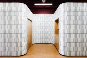 A modern bathroom with white tiled walls and beige flooring.