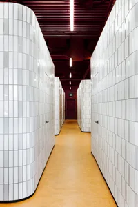 A modern industrial public space featuring white tiled walls and a yellow floor with a red ceiling.