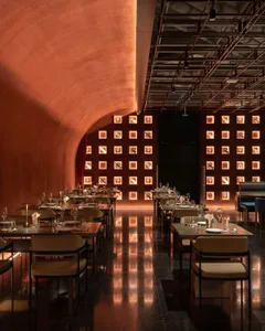 A modern, industrial-inspired dining room with metallic textures, square light fixtures, and sleek furniture.