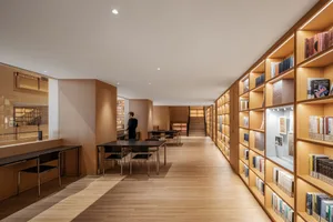 Industrial-style library interior with wooden shelves and tables.
