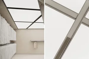 Minimalist clothing boutique interior with concrete walls, glass windows, and hanging suit jackets.