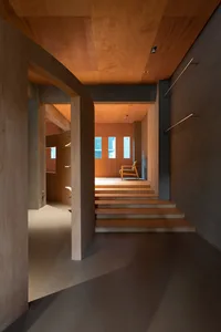 A minimalist wooden interior space with a staircase and a chair.