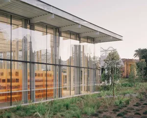 A modern building exterior featuring large glass panels and a steel structure.