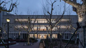 A modern metallic exterior building at dusk with illuminated windows.