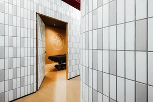 A modern health spa with white tiled walls, a concrete floor, and wooden accents
