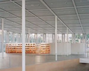 現代圖書館室內，混凝土牆面、玻璃隔間，以及木質閱讀區。