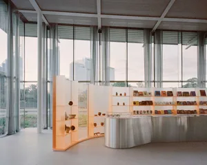 A modern library interior featuring glass walls, a steel counter, and various light fixtures.