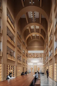 People sitting at tables in a spacious library with wooden shelves and high ceilings.