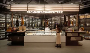 Modern retail storefront with a cheese and charcuterie counter, featuring wooden counters and glass display cases.