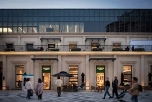 A modern exterior of a shopping center with glass storefronts and stone accents.