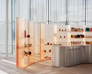 Modern library interior with glass shelves displaying books and artifacts.