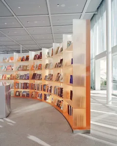 A modern library with glass and metal shelves filled with books.