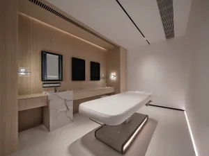 A minimalist medical room with wooden walls and a white bed.