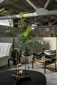A spacious, industrial-style living room featuring wood furniture, leather accents, and concrete walls.