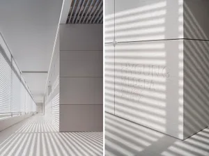 極簡走廊，混凝土牆面呈現由垂直窗戶透入的陽光所形成的紋理圖案，