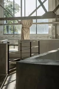 A minimalist interior space featuring exposed concrete and steel elements.
