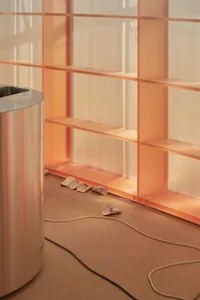 An indoor minimalist design featuring a glass wall and metallic cylinder container.