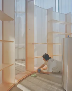 Person cleaning a minimalist interior with white acrylic and copper materials