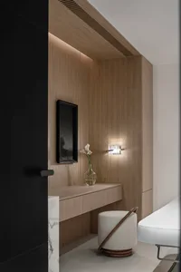 A minimalist interior design featuring a wooden frame with a vase of flowers and a white ottoman.
