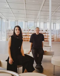 一位女士與一位男士坐在擁有混凝土與玻璃元素的現代休憩區。