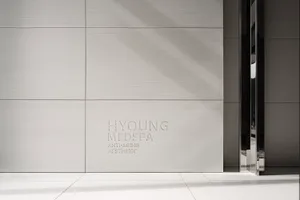 A sleek, white concrete wall with a logo and text in the center.