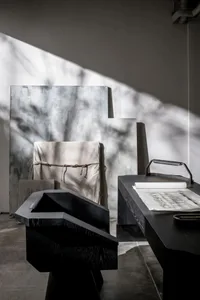 A minimalist modern workstation featuring a wooden desk with a metal object, viewed under soft, natural light.