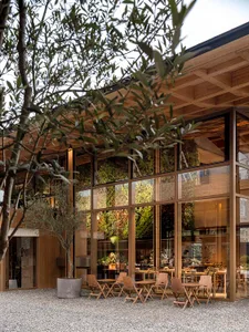 A modern restaurant exterior with large glass walls and wooden furniture