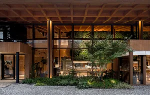 A modern restaurant exterior featuring a wooden and glass facade with greenery.