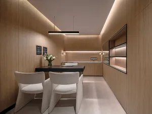 A minimalist office space featuring wood panels, a black table with white chairs, and a sleek design.